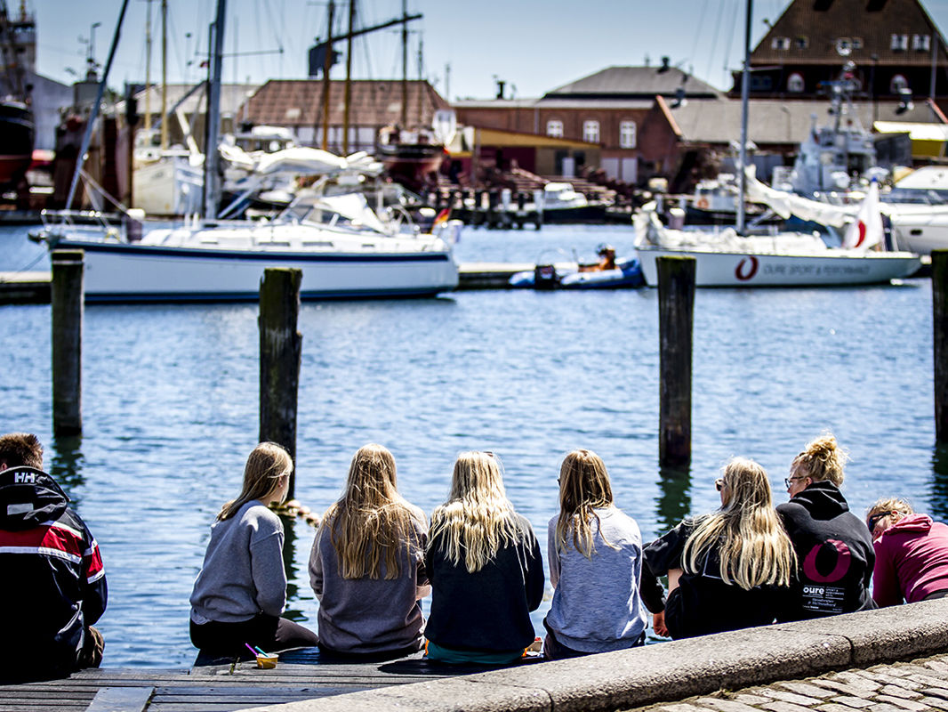 Unge sidder på kajkanten